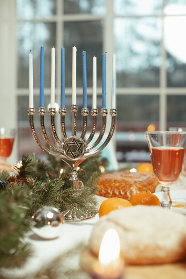 A Menorah on a table surrounded by food and drink.